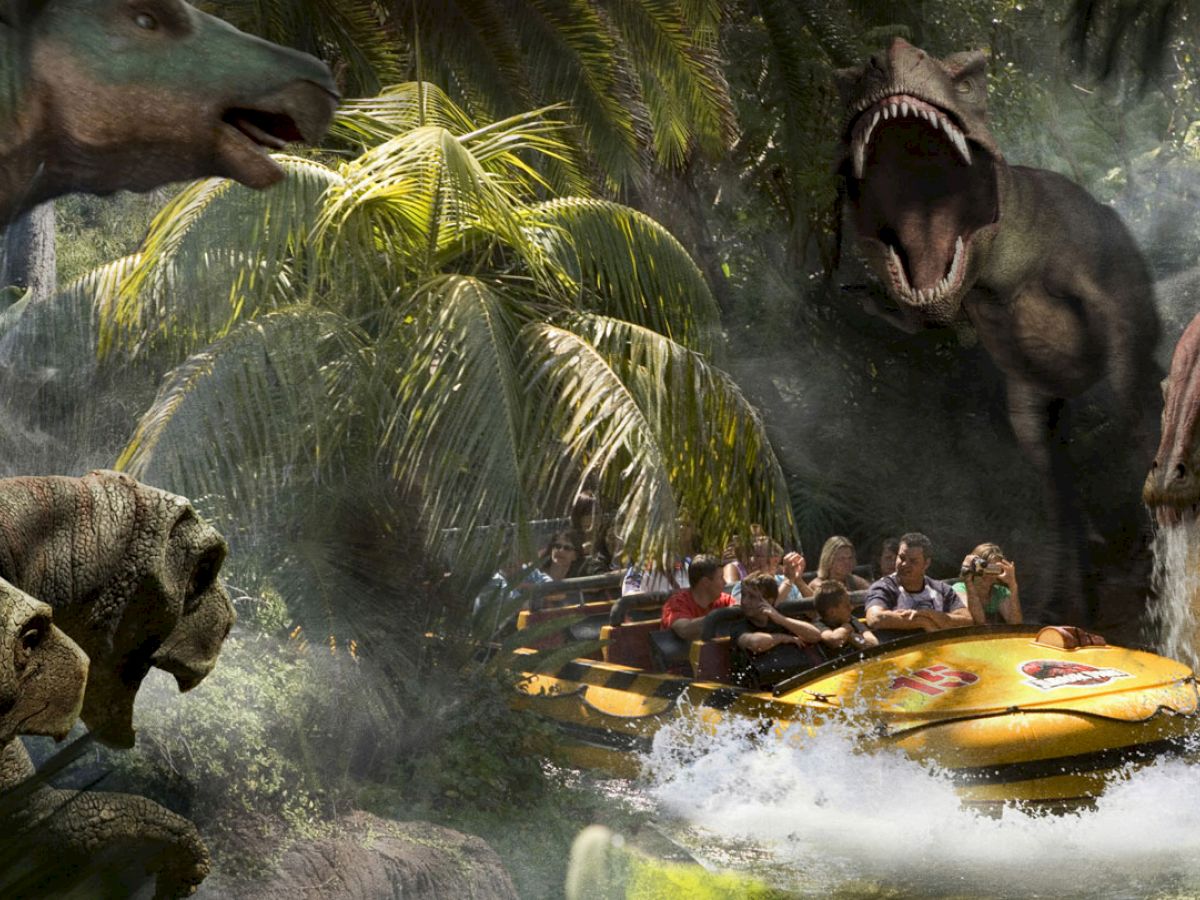 People on a theme park river raft ride are surrounded by animatronic dinosaurs, including a large roaring T-Rex, in a jungle setting.