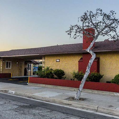 The image shows a single-story motel with a red and yellow facade. A sign reading "Motel" in red letters on a white background is also present.