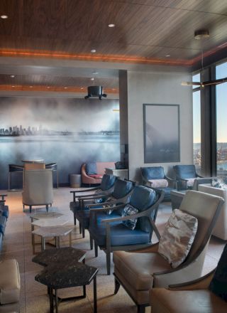 A modern lounge with comfortable seating, large windows showcasing a waterfront view, and a stylish wall mural depicting a city skyline ends the sentence.